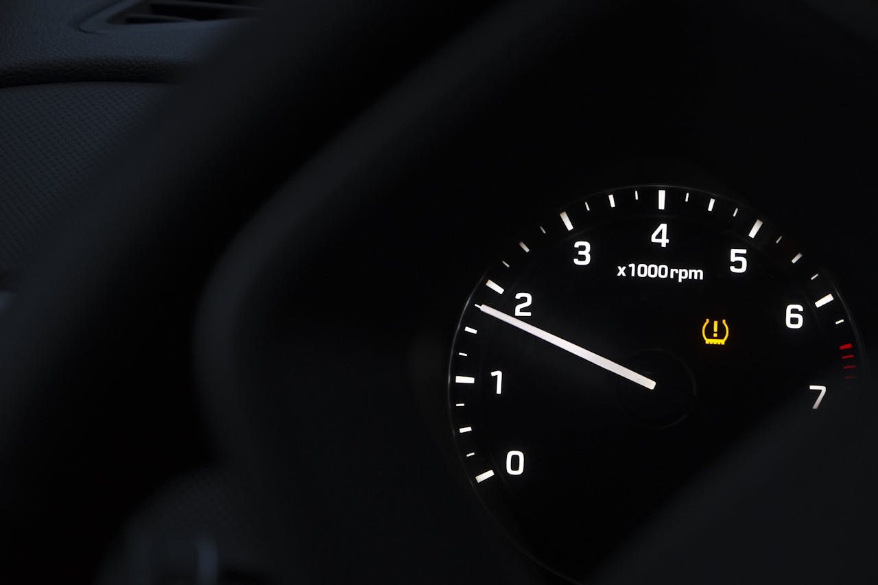 The amber TPMS warning light — a horseshoe shape with an exclamation point — illuminated on a vehicle dashboard. Under FMVSS No. 138, the light must trigger when any tire is 25 percent or more below the manufacturer recommended pressure.